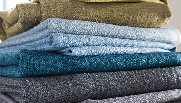 Stack of fabrics showing range of colours from greys to blue - Blinds Norfolk - Norwich Sunblindss to taupe